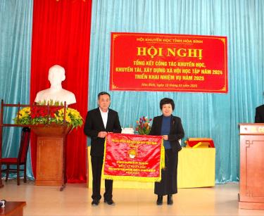 Đồng chí Nguyễn Thị Oanh, Chủ tịch Hội Khuyến học tỉnh trao cờ đơn vị xuất sắc của TW Hội cho Hội Khuyến học Lạc Sơn.